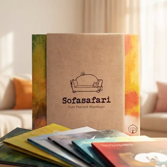 Sofasafari-Produktbox mit Sofa-Illustration und Text „Sofasafari – Euer Paarzeit Abenteuer" auf neutralem Untergrund. Box mit Bandarole wird von Händen gehalten. Symbolisiert die Verpackung des perfekten Paar-Geschenks, zu Geburtsatgen, Hochzeiten oder Jahrestagen.