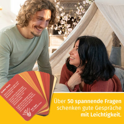 Paarzeit PaarMinuten Fürs Herz im Zelt – Paar sitzt zusammen im weißen Zelt mit weißer Lichterkette, hält Fragekarten und lacht gemeinsam zum Valentinstag