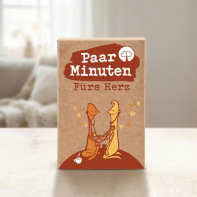 Paarzeit PaarMinuten Fürs Herz Produktshot – Kartenset mit rotem Logo auf Tisch mit Sofa im Hintergrund
