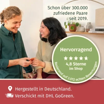 Paarzeit PaarMinuten Doppelpack Glücksgefühl und Tiefgang Paare Bewertung – Paar mittleren Alters bei warmem Sonnenuntergang mit brennender roten Kerze, hält rote Kartenbox, grüner Kreis mit 5 Sternen, Text 4,8 Sterne im Shop, Schon über 300.000 zufriedene Paare seit 2019, grünes Paarzeit-Logo, Text Hergestellt in Deutschland und DHL GoGreen Versand zum Valentinstag