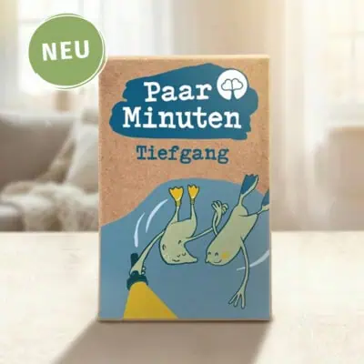 aarzeit PaarMinuten Tiefgang NEU – Kartenset mit 53 Gesprächsimpulsen zu tiefgründigen Themen und emotionaler Verbindung, Box mit blauem Logo auf Tisch mit Sofa im Hintergrund