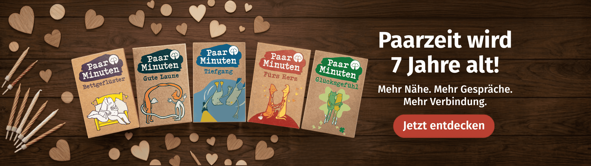 5 PaarMinuten Kartenspiele auf einem Holztisch mit Holzherzen zum 7. Paarzeit Jubiläum. Slogan: Mehr Nähe. Mehr Gespräche. Mehr Verbindung.
