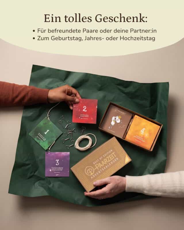 Von oben: die goldene Schachtel des Paarzeit Adventskalenders BEST OF EDITION liegt geöffnet auf dunkelgrünem Seidenpapier, daneben vier nummerierte Kalenderkärtchen in Grün, Rot, Violett und Orange, aufgerollte Kordel und Metallklammern; zwei Hände greifen ins Bild. Eingeblendet: „Ein tolles Geschenk: Für befreundete Paare oder deine Partner:in · Zum Geburtstag, Jahres- oder Hochzeitstag“
