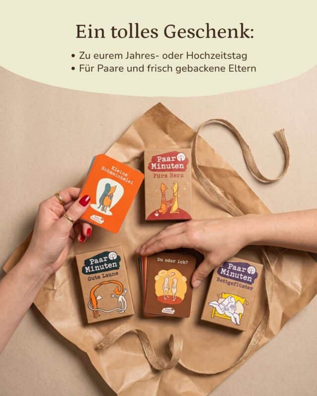 Von oben: auf Kraftpapier liegen die Schachteln PaarMinuten Fürs Herz, Gute Laune und Bettgeflüster mit einem Kartenstapel der Kategorie „Du oder ich?“; eine Hand hält eine orangefarbene Karte „Kleine Schmeichelei“ ins Bild. Eingeblendet: „Ein tolles Geschenk: Zu eurem Jahres- oder Hochzeitstag · Für Paare und frisch gebackene Eltern“