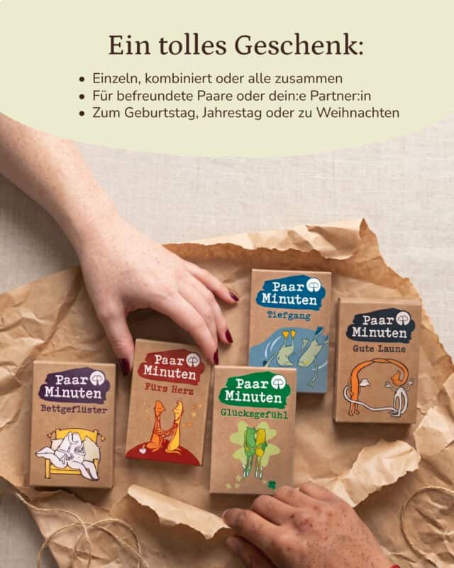 Aufsicht auf zerknittertes Packpapier, auf dem die fünf PaarMinuten-Kartensets in ihren Kraftpapier-Schachteln liegen: Bettgeflüster, Fürs Herz, Glücksgefühl, Tiefgang und Gute Laune, jede mit ihrer farbigen Illustration zweier Figuren. Von oben links greift eine Hand mit rot lackierten Nägeln nach einer Schachtel, von unten rechts kommt eine zweite Hand ins Bild. Eingeblendet: „Ein tolles Geschenk: Einzeln, kombiniert oder alle zusammen. Für befreundete Paare oder dein:e Partner:in. Zum Geburtstag, Jahrestag oder zu Weihnachten.“
